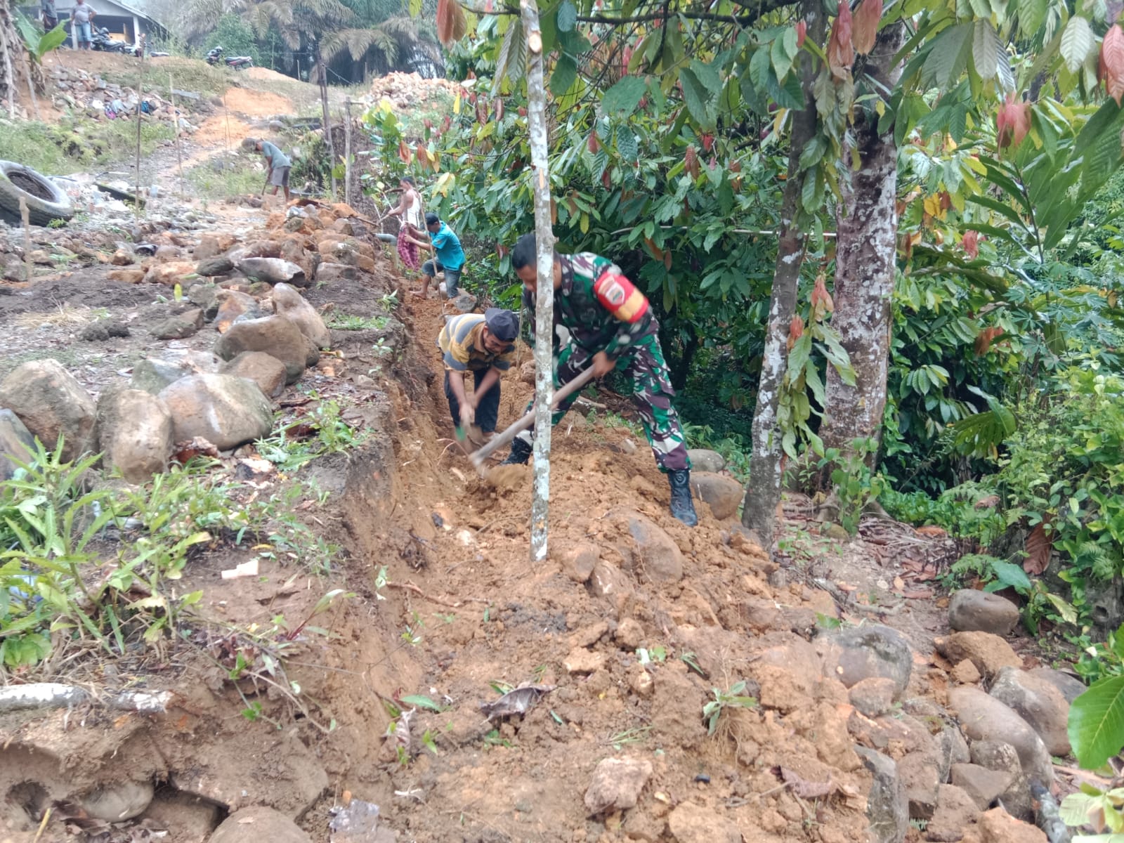 Keterangan Foto: Babinsa Koramil 05/Kolang, Serda Benni Sitompul membantu percepatan pembangunan Jalan Rabat Beton di Desa Bonan Dolok, Kabupaten Tapteng, Senin (10/07/2023).