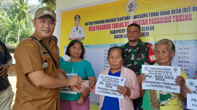 Foto : Kepada Desa Pasaribu Tobing, Diswanto Hutagalung saat menyerahkan langsung BLT kepada Keluarga Penerima Manfaat.